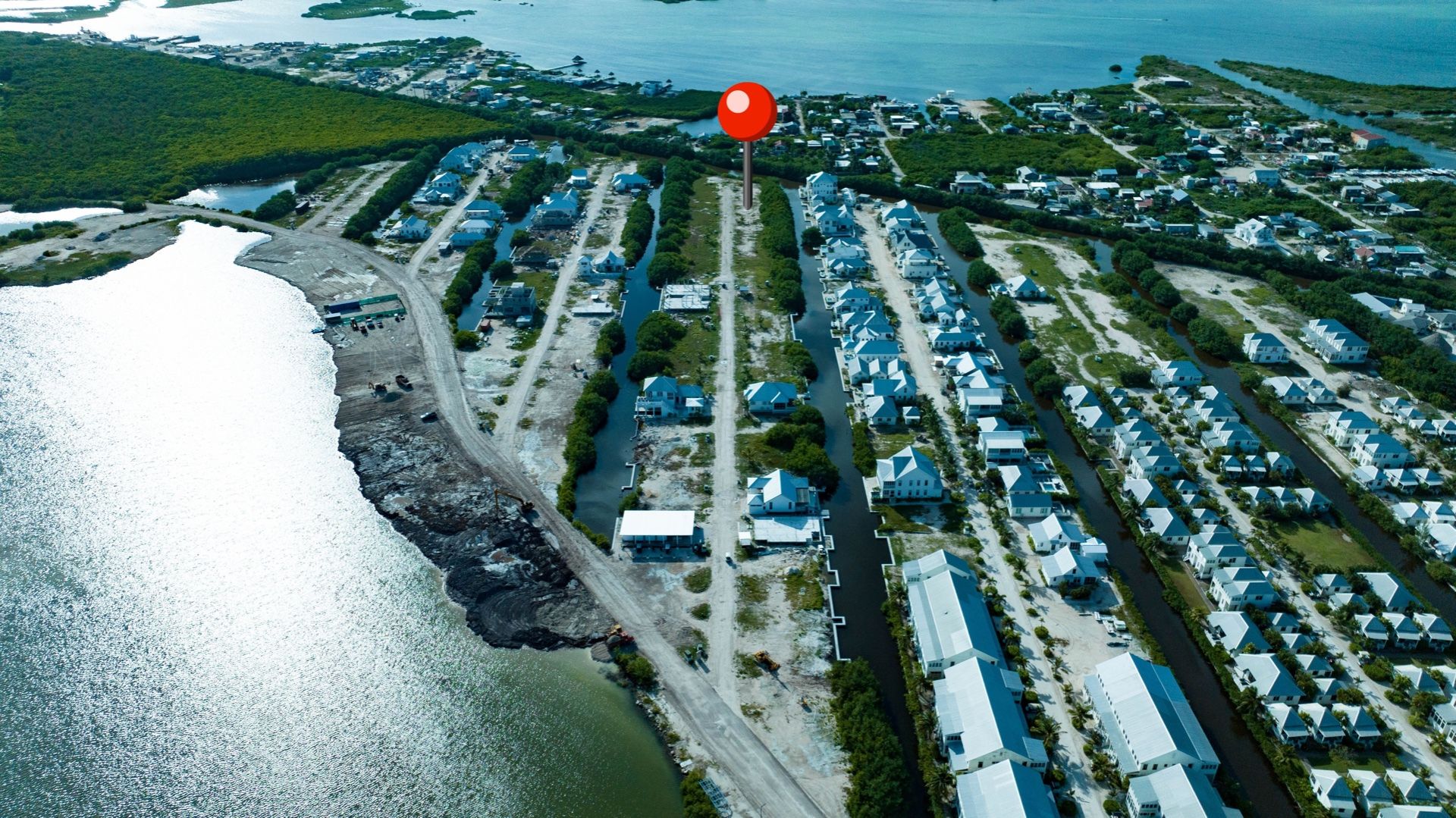 Aerial view of a cleared lot beside a canal lined with houses and water