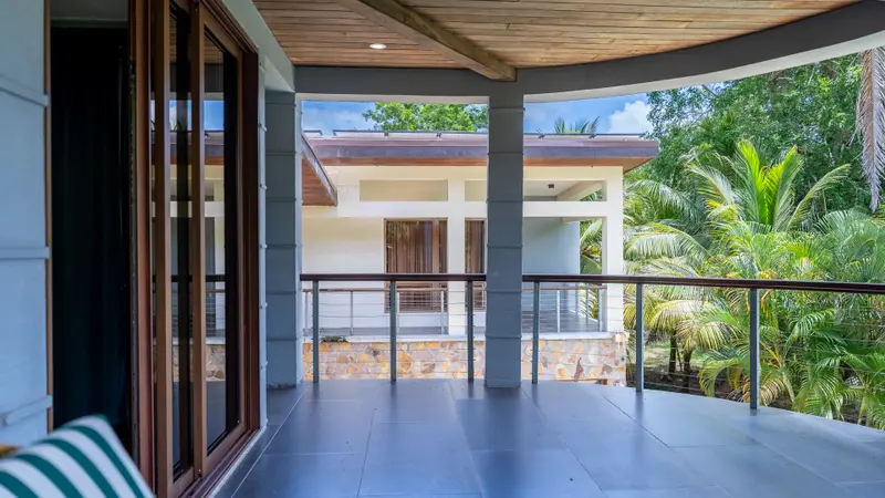 Covered terrace with grey tile floor, cable railing and stone wall