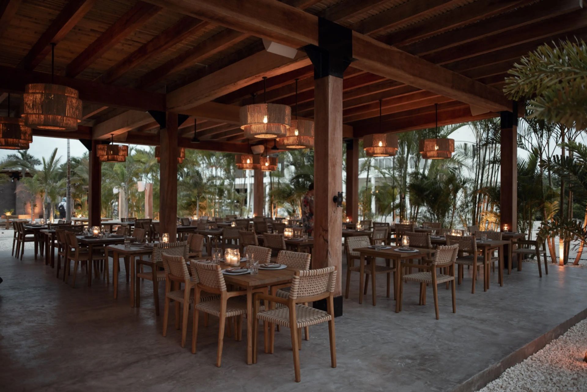Open-air dining room with woven rattan pendant lights and wooden tables