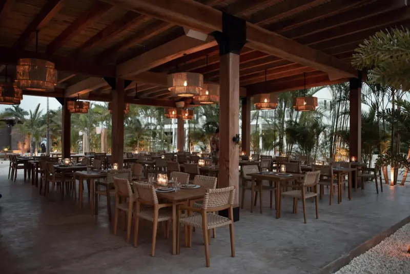Open-air dining room with woven rattan pendant lights and wooden tables