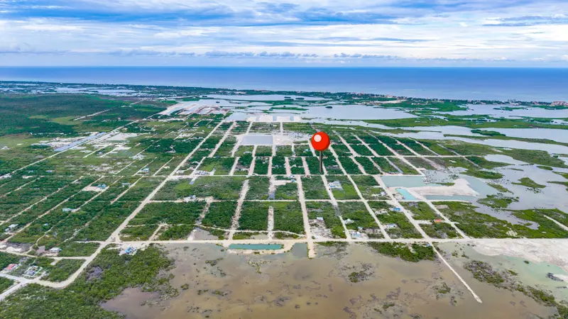 Aerial view of a gridded lot subdivision with scrub vegetation and sea beyond