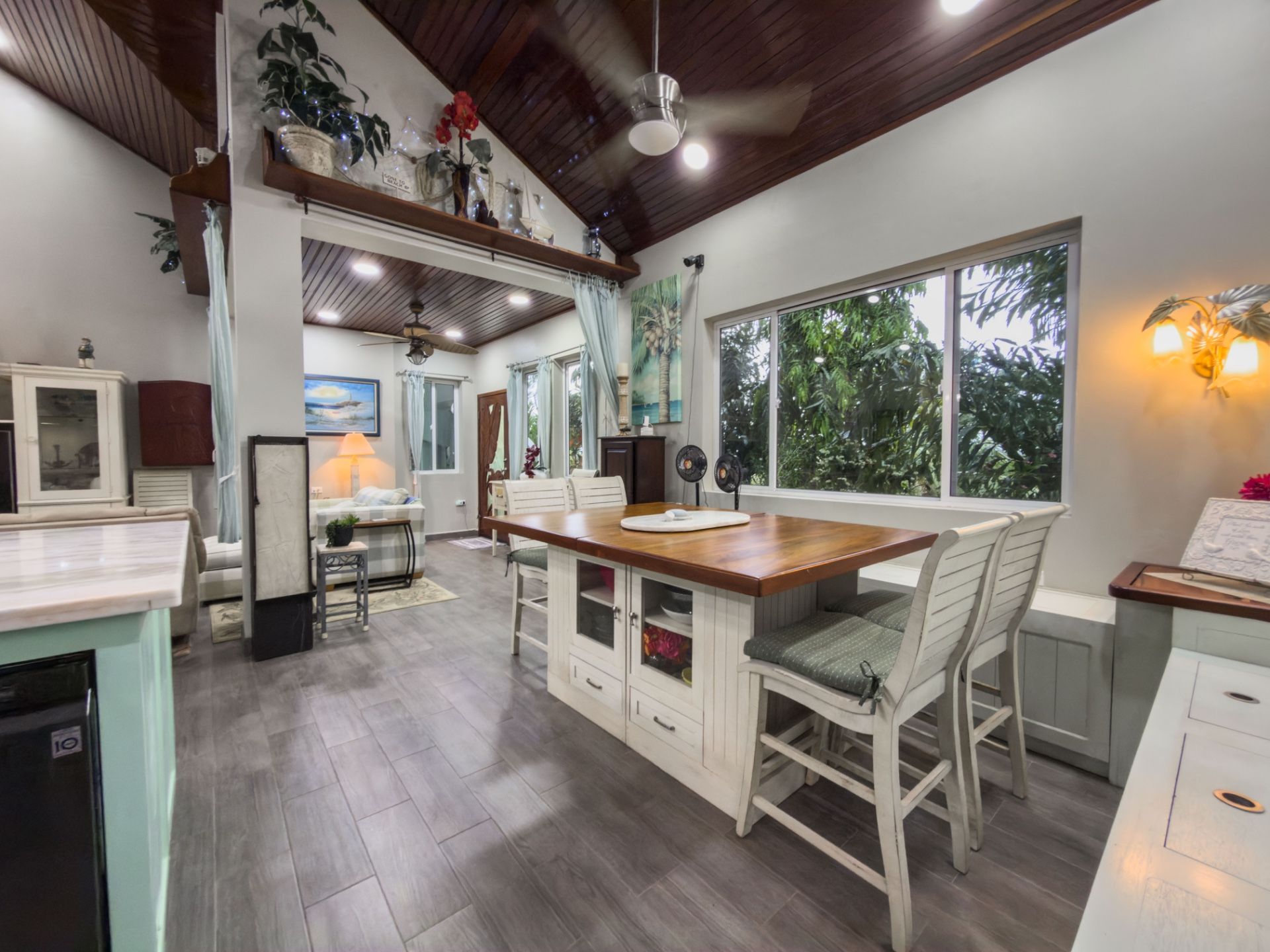 Open kitchen island with wood countertop, white cabinets and green-cushioned stools