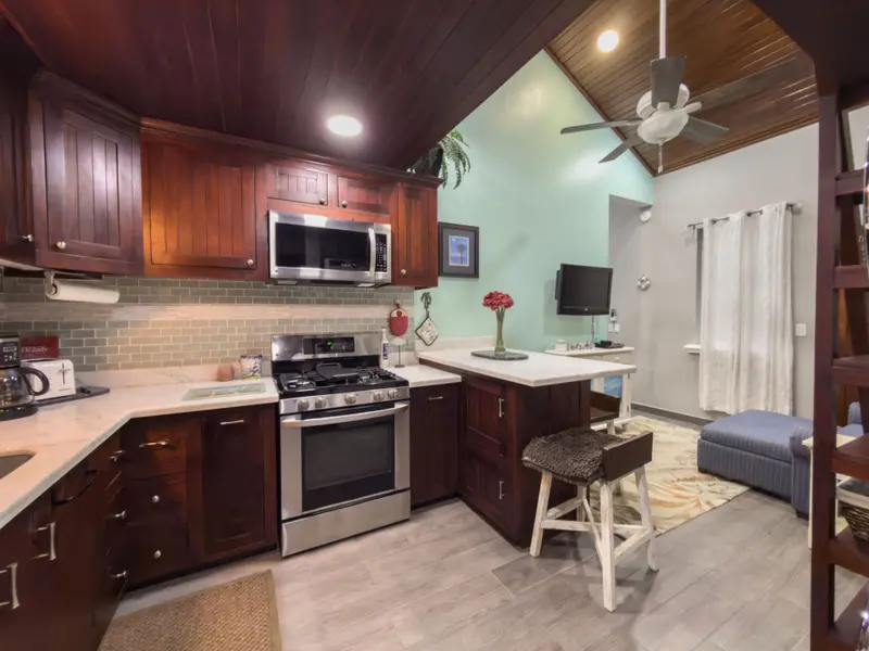 Compact kitchen with dark wood cabinets, stainless gas range and mint green walls