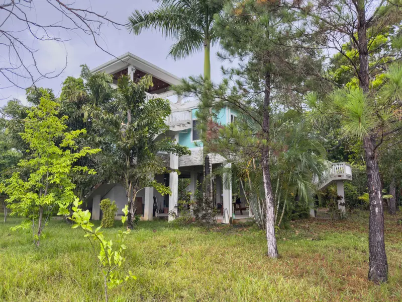 Two-storey house with turquoise walls, white balcony and stone-clad lower level