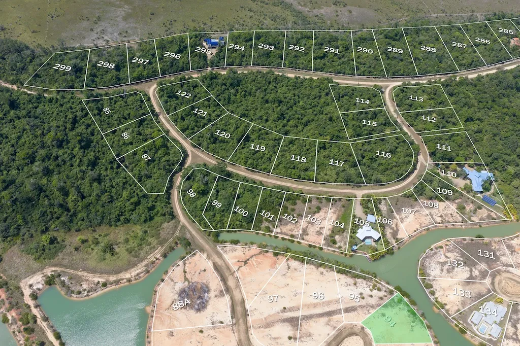 Aerial view of numbered residential lots among dense trees beside a green waterway
