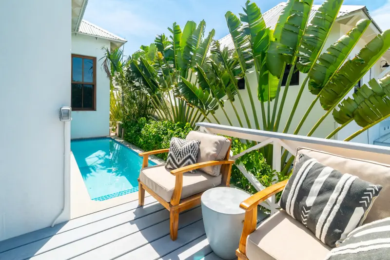 Teak armchair with cushions beside a pool and tropical banana plants