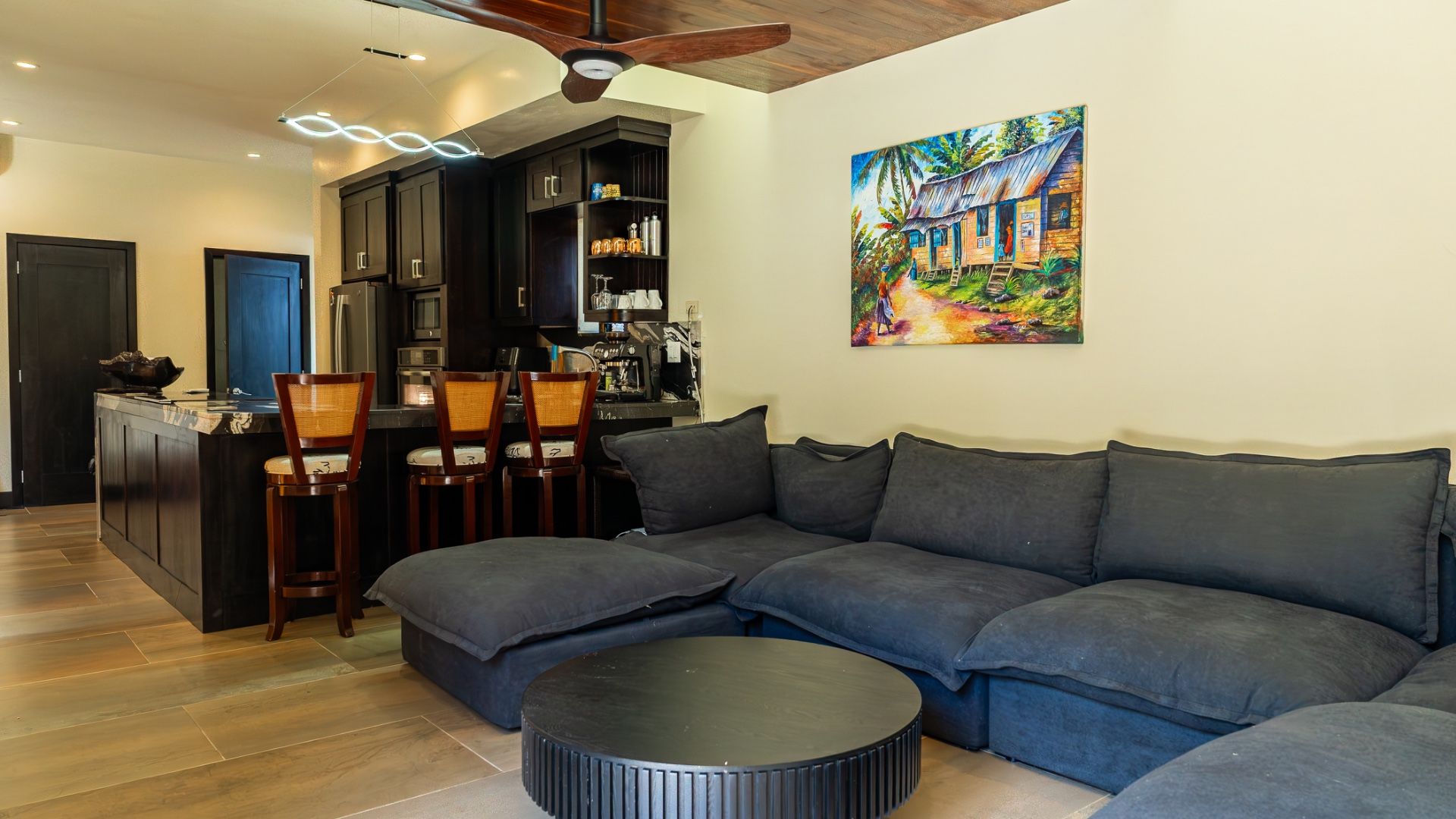 Living room with dark gray sectional sofa and colorful painting of a cottage