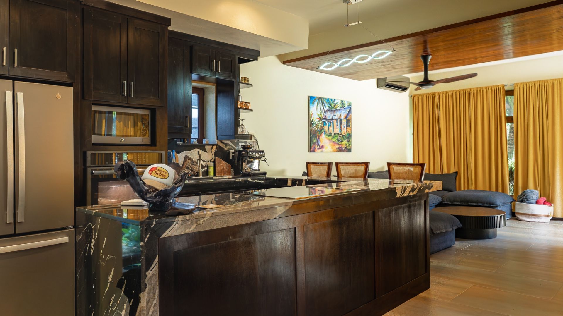 Kitchen counter with dark wood cabinets, espresso machine and painting of a wooden house