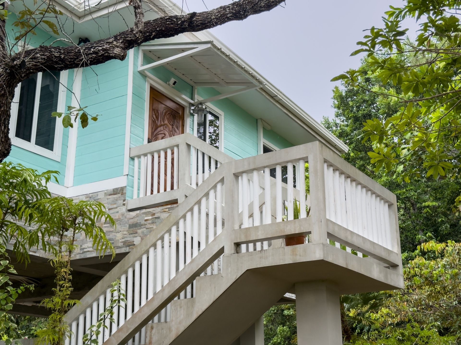 Mint green house facade with carved wooden door and white railed staircase