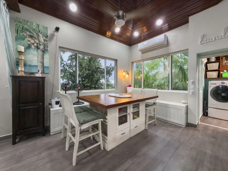 Kitchen island with wood countertop and white stools by windows