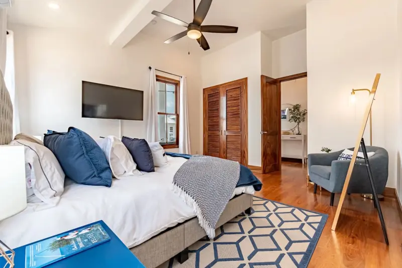 Bedroom with white bedding, navy pillows and louvered wood closet doors
