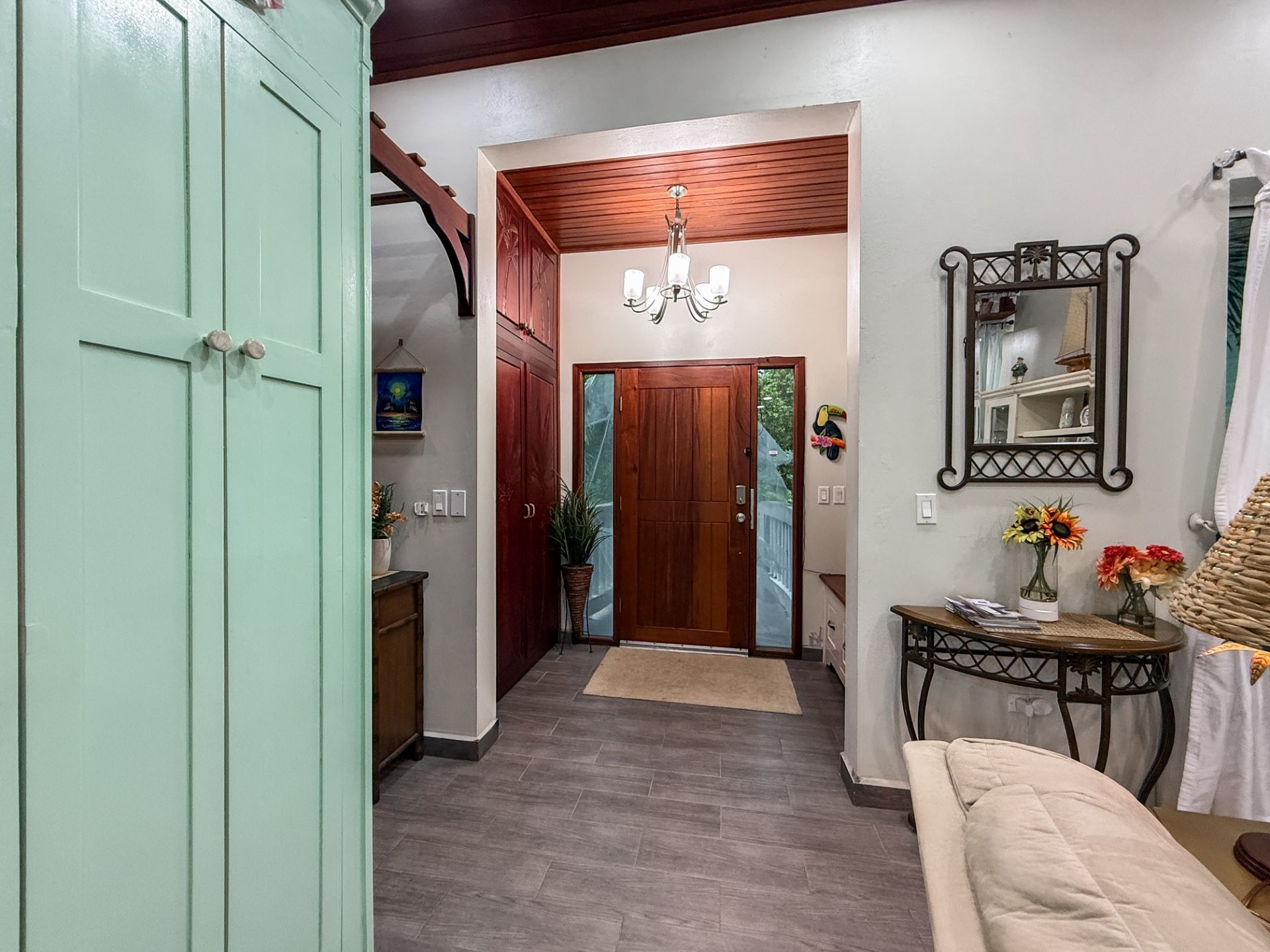 Entryway with wooden front door, glass sidelights and a frosted chandelier