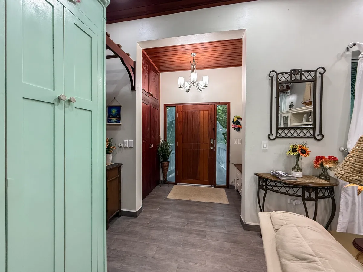 Entryway with wooden front door, glass sidelights and a frosted chandelier