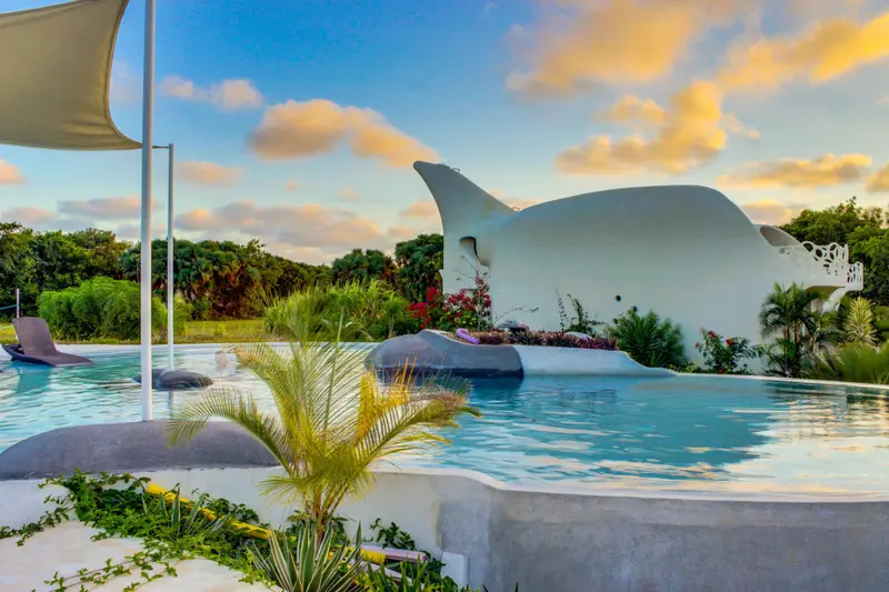 Pool beside a white sculpted building shaped like a manta ray