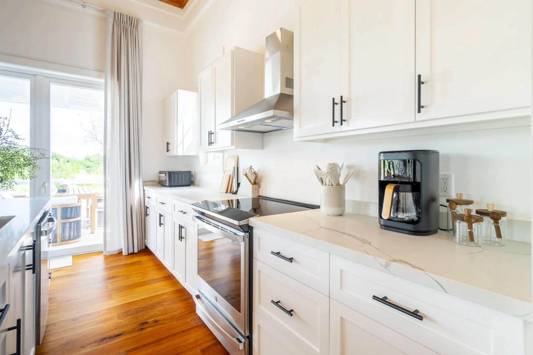 Kitchen with white shaker cabinets, stainless range hood and marble-look countertops
