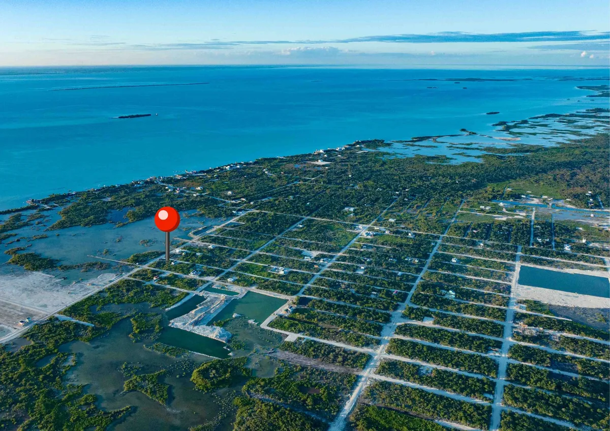 Aerial view of a gridded lot subdivision along turquoise sea with scattered buildings
