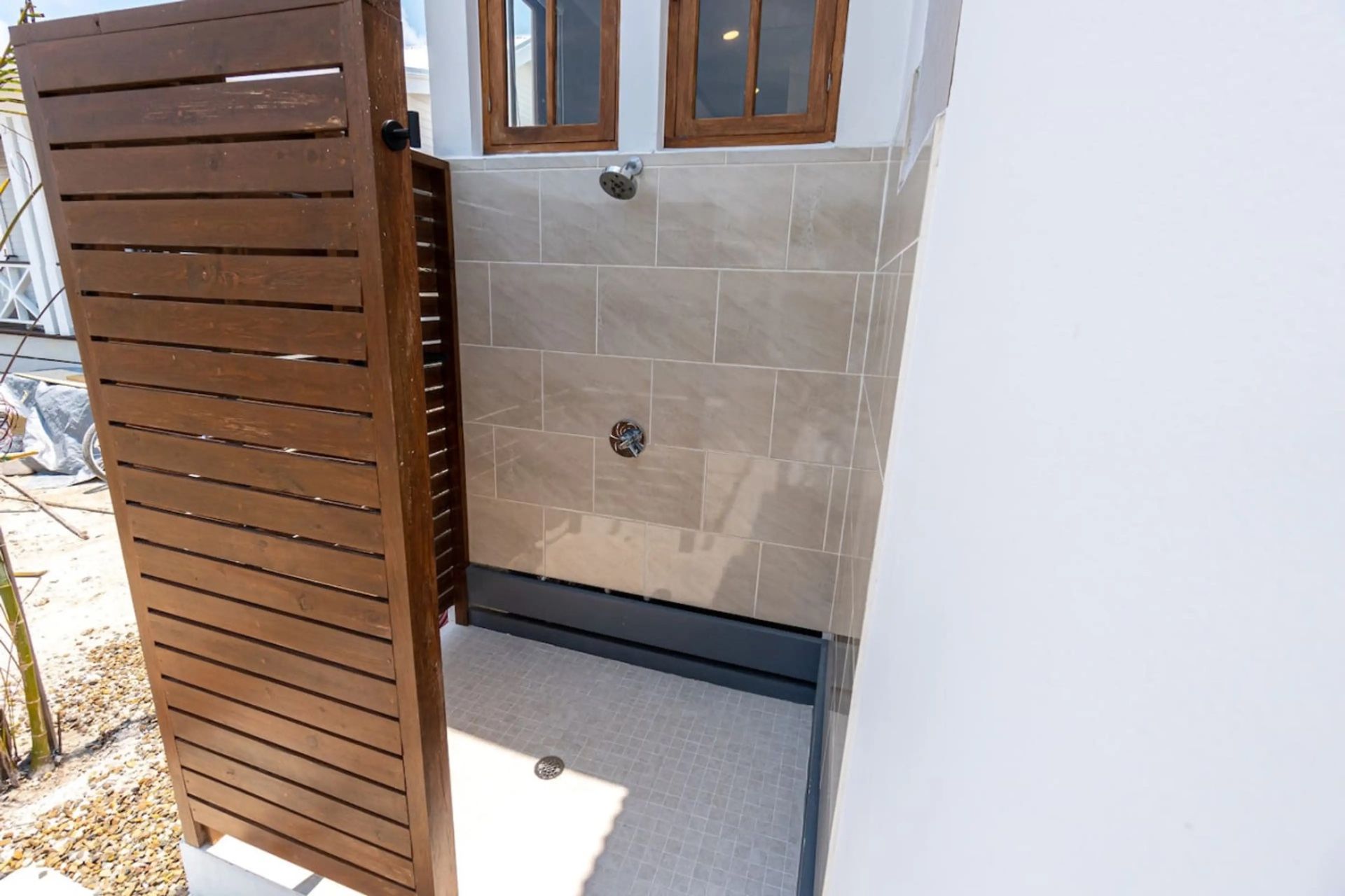 Outdoor shower with large taupe tiles and small grey floor tiles