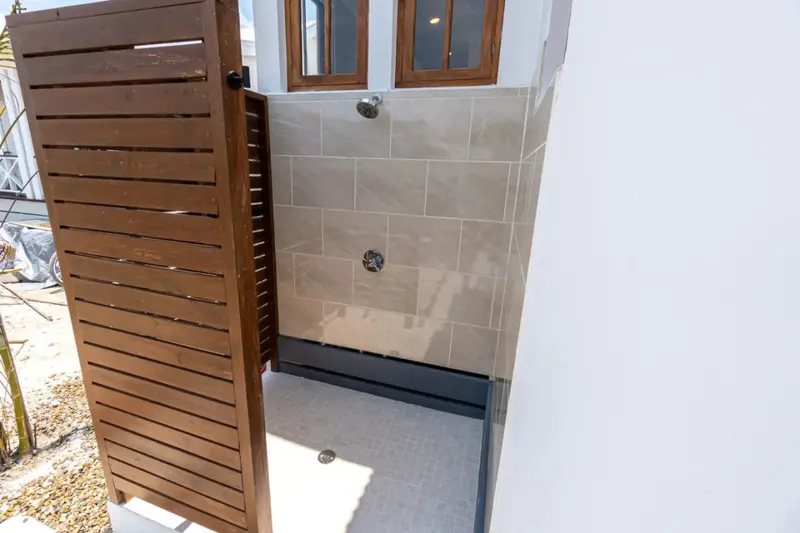 Outdoor shower with large taupe tiles and small grey floor tiles