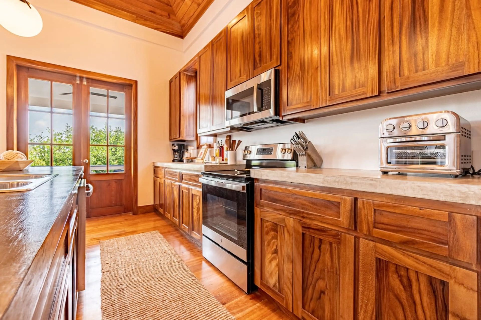 Galley kitchen with warm wood cabinets and stainless steel range
