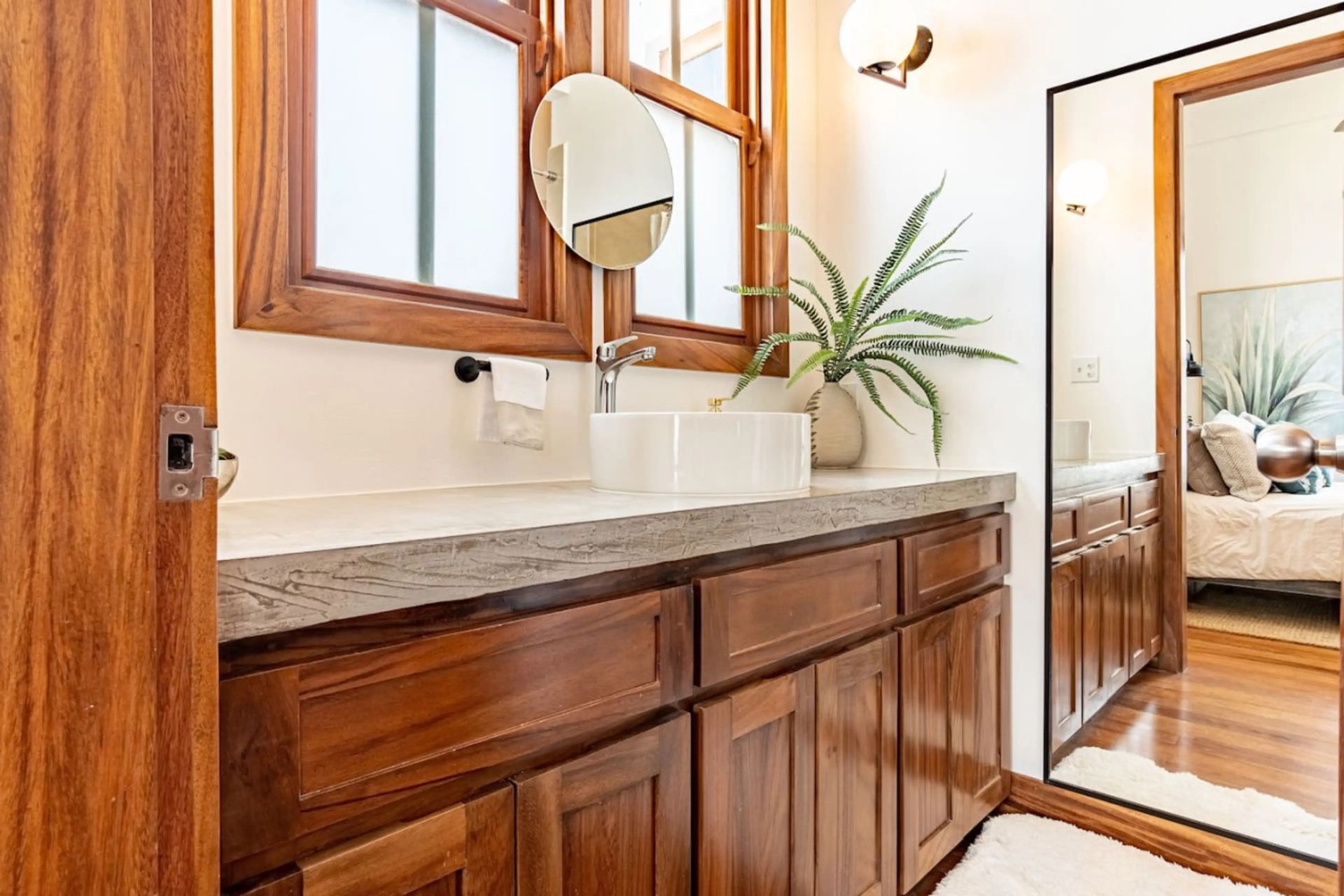 Bathroom vanity with wood cabinets, white vessel sink and round mirror