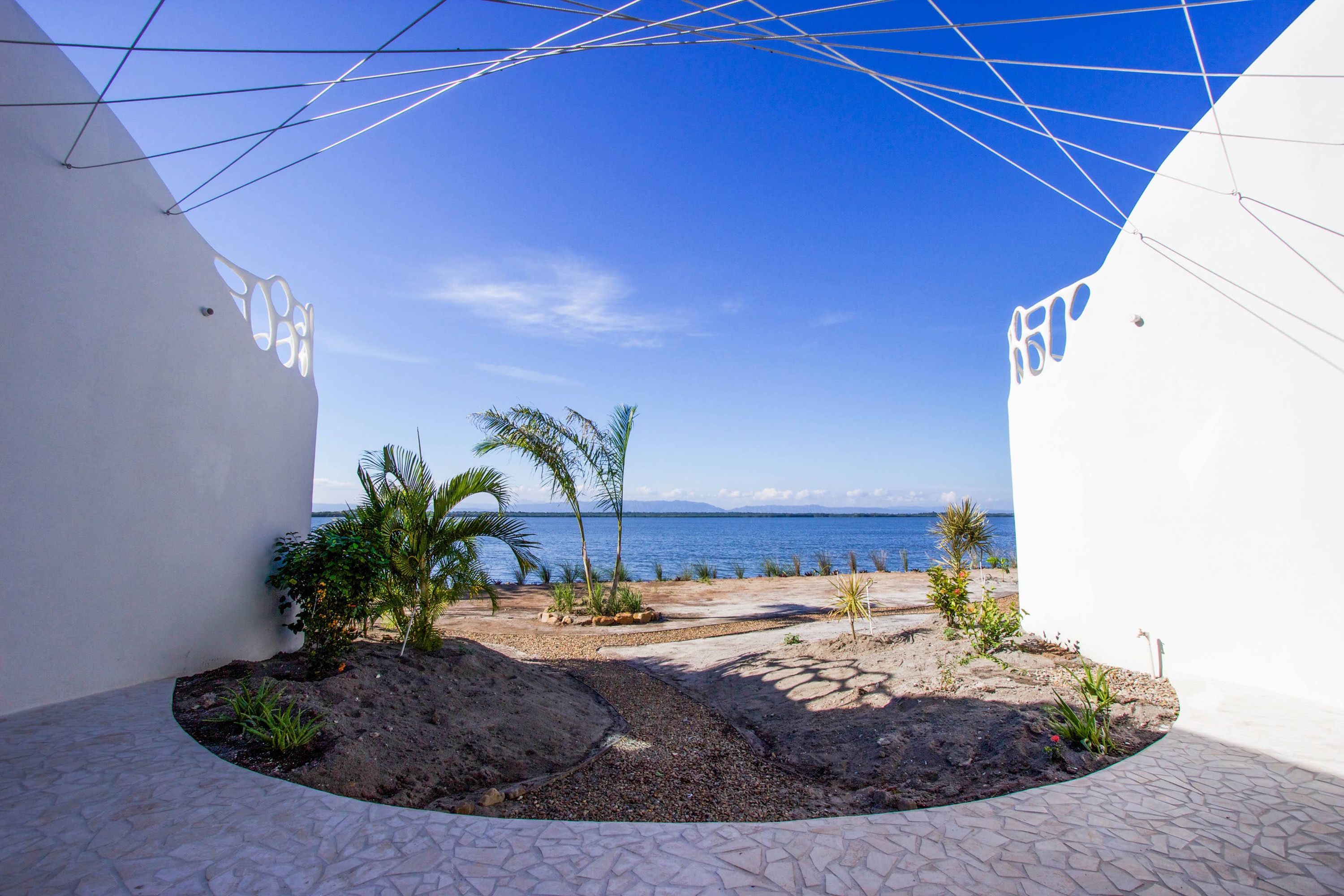 Gravel and stone path leading to lake shore with young palm trees