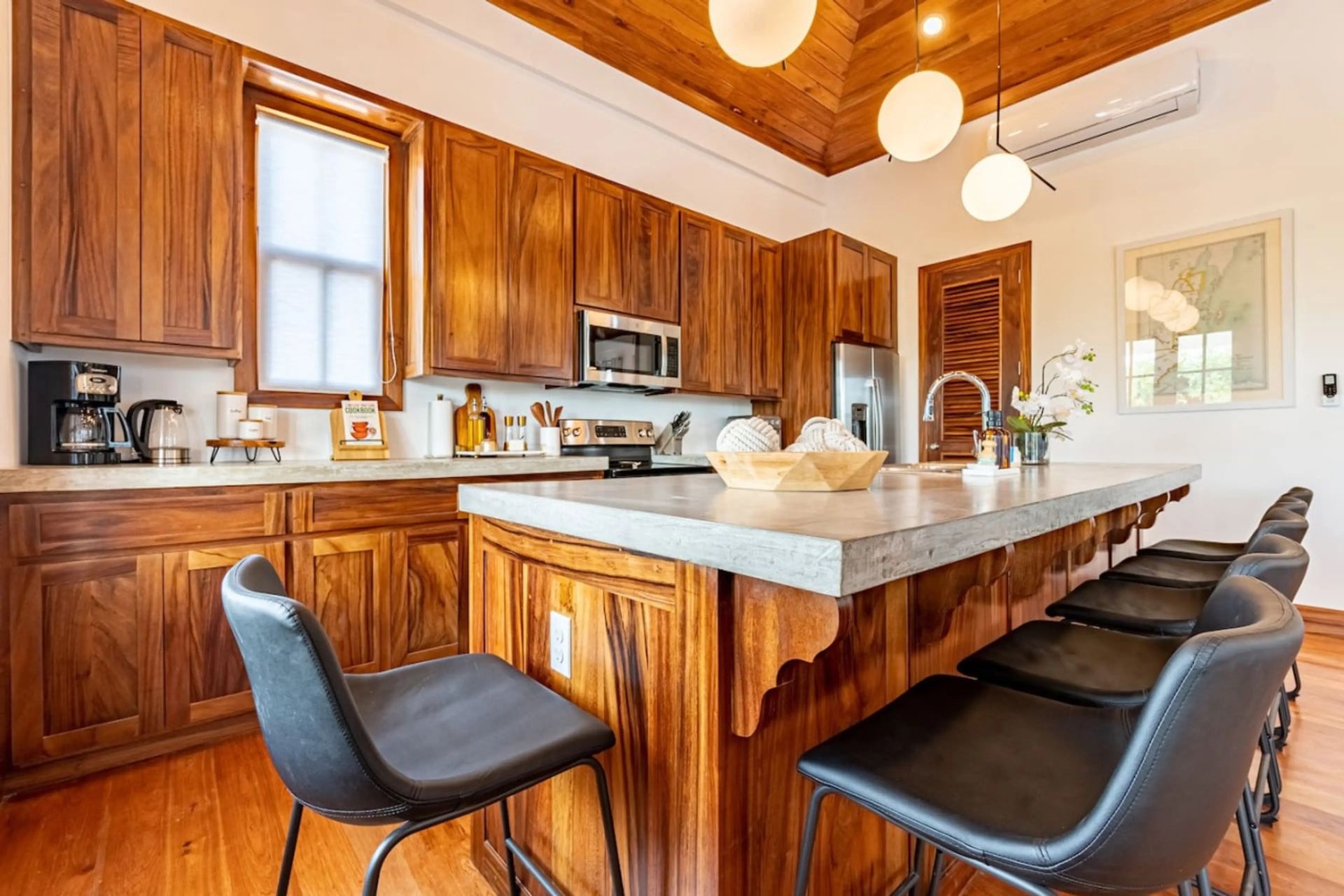 Kitchen with wood cabinets, concrete-look island countertop and black stools