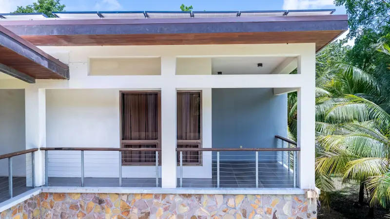 Covered terrace with wood-framed windows, cable railing and stone base