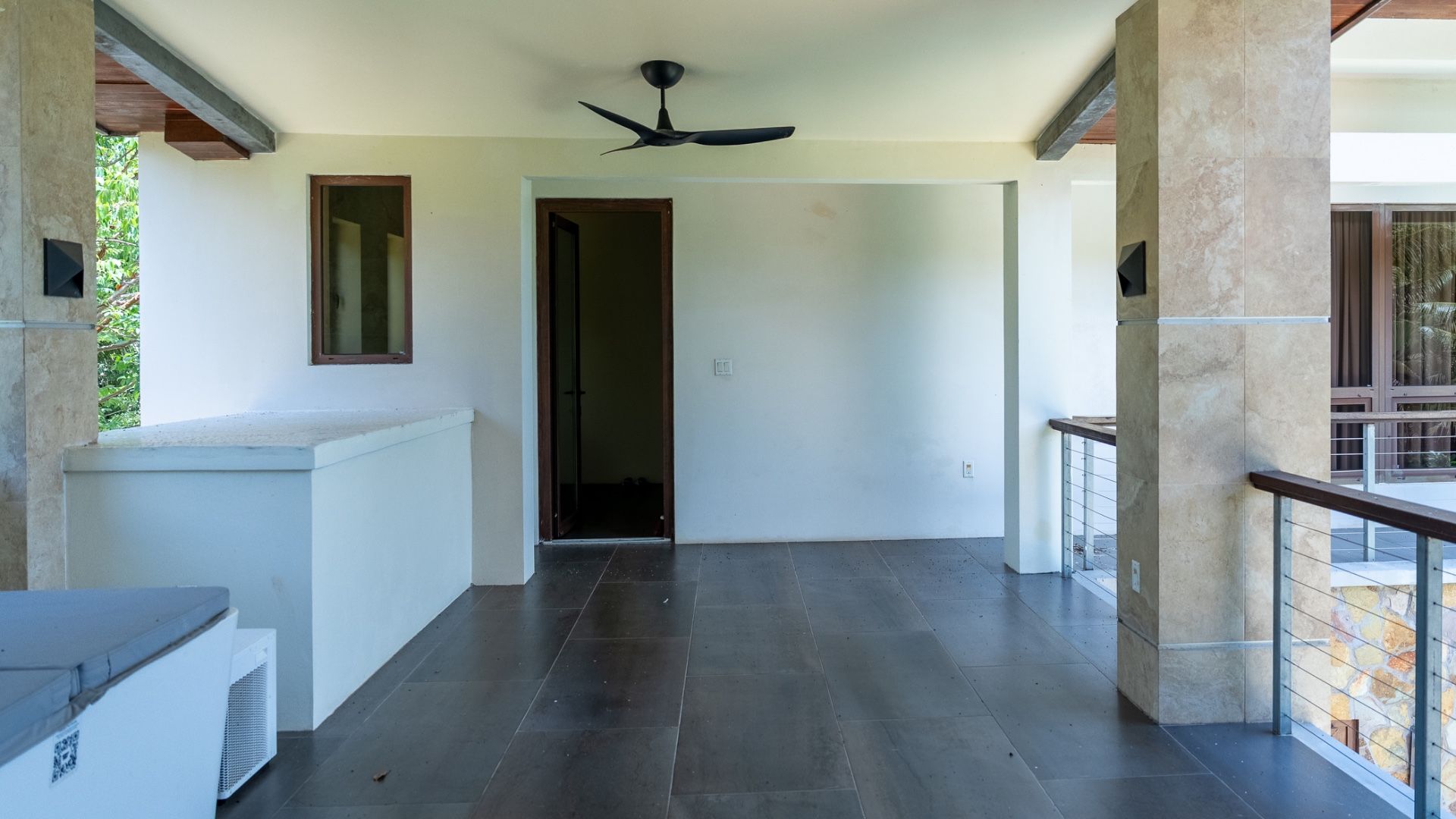 Empty room with dark tile floor, black ceiling fan and open doorway