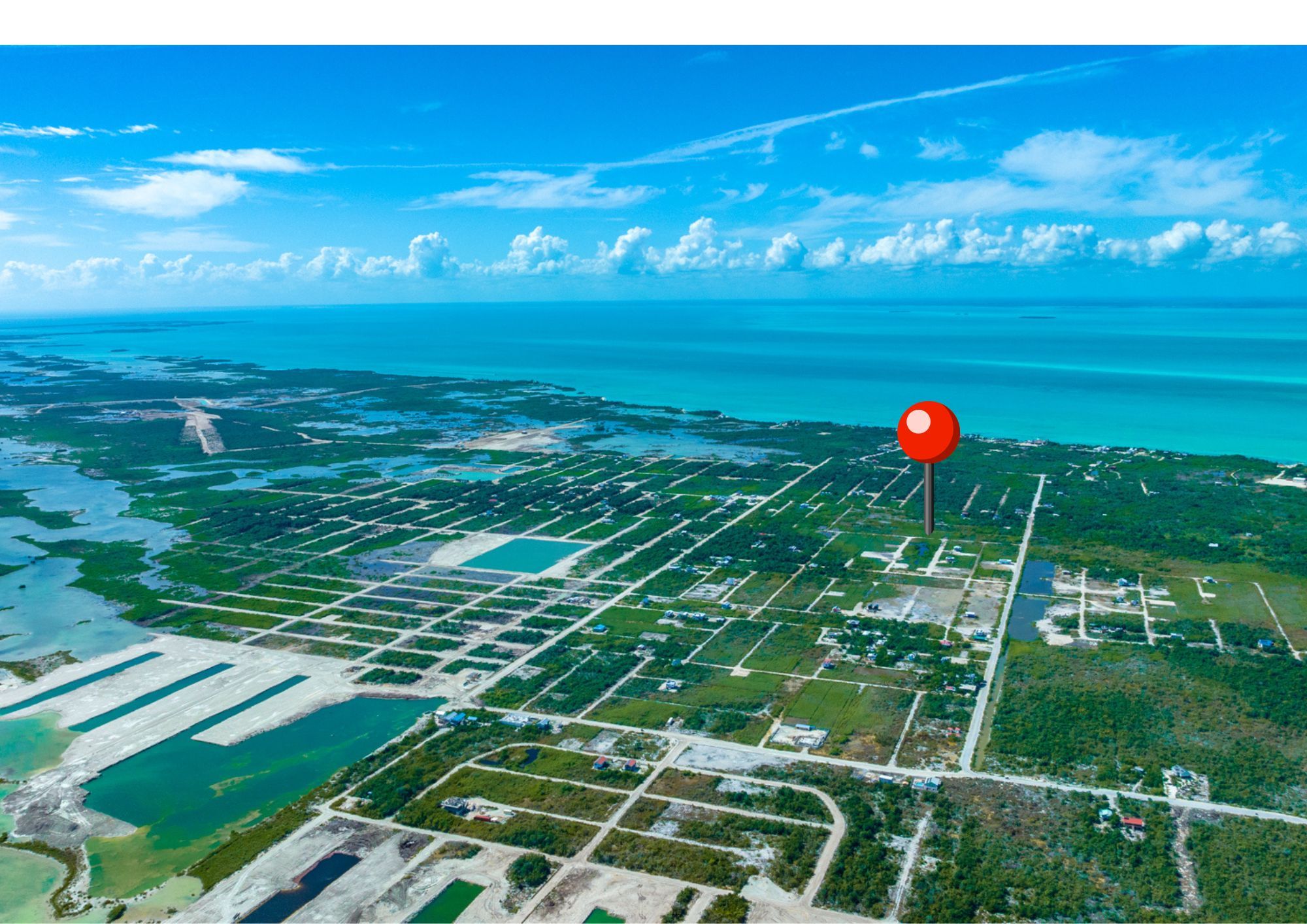 Aerial view of gridded land parcels with scattered buildings along turquoise sea