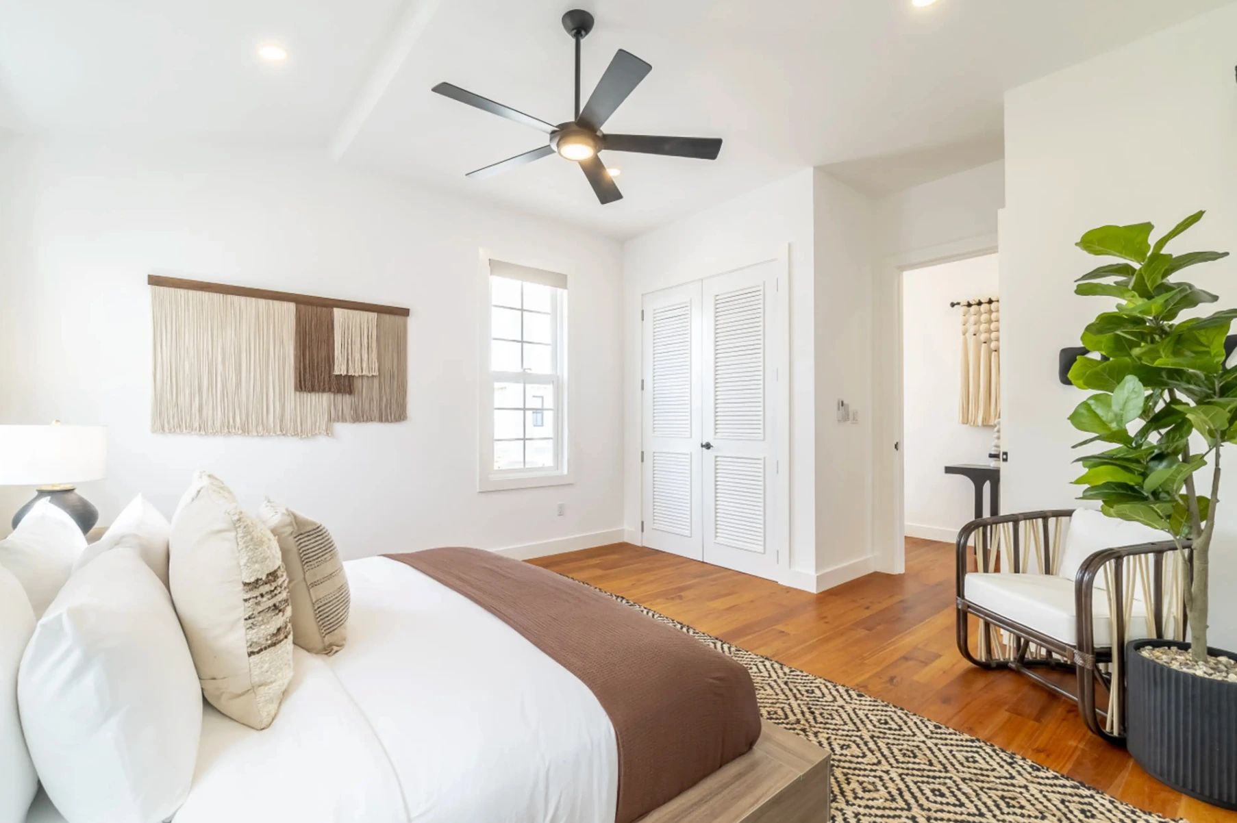 Bedroom with white bed, black ceiling fan, and louvered bifold closet doors