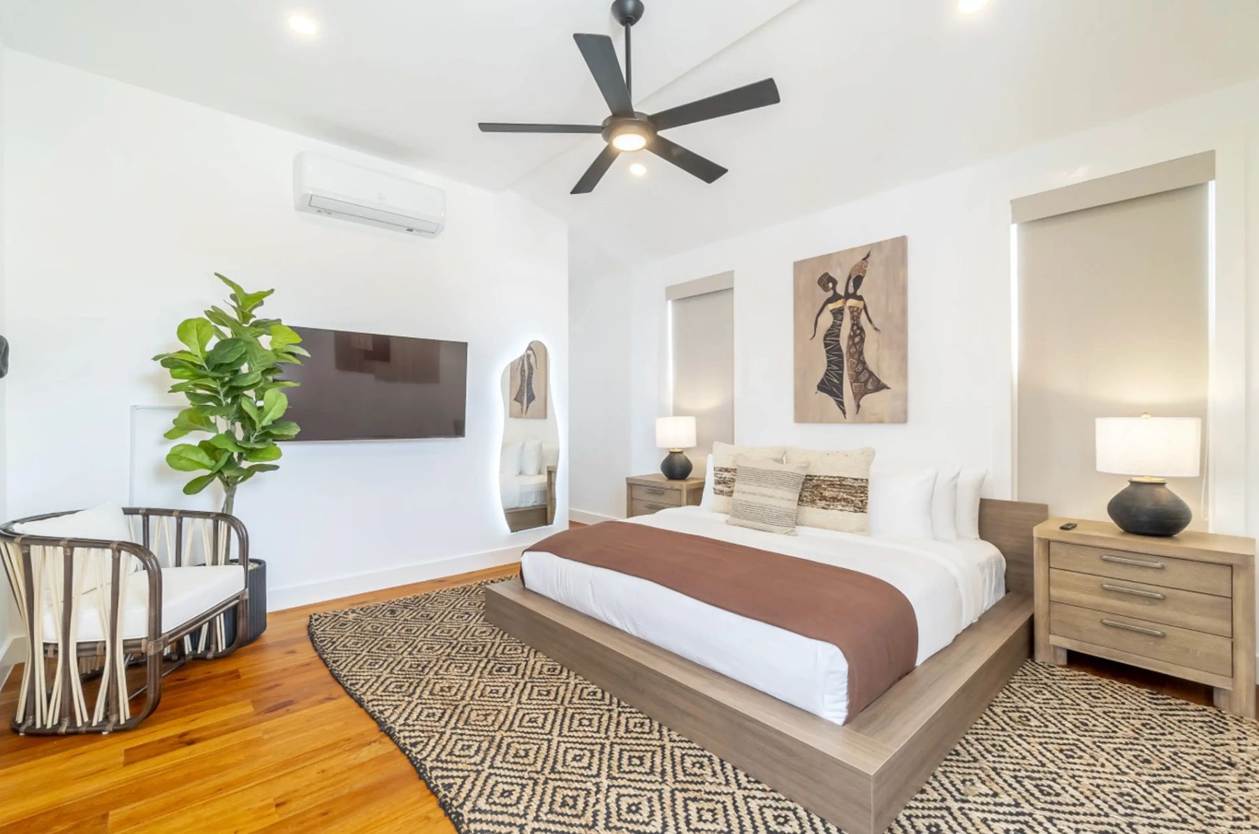 Bedroom with platform bed, black ceiling fan and diamond patterned jute rug