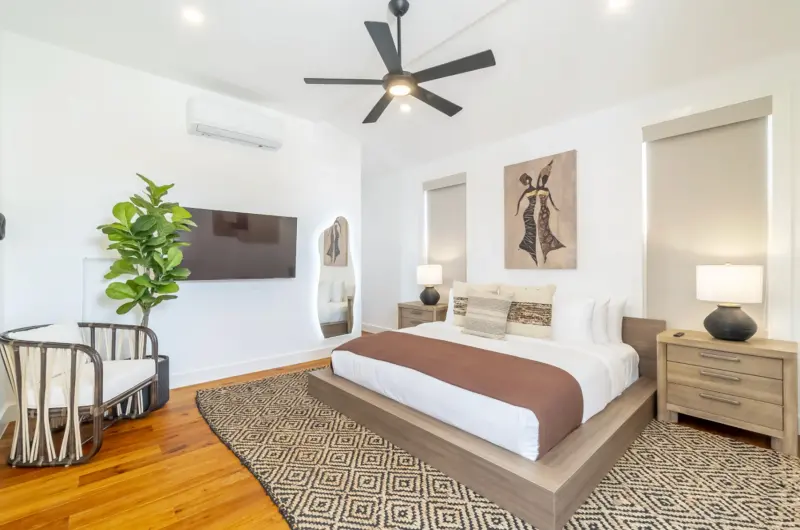 Bedroom with platform bed, black ceiling fan and diamond patterned jute rug