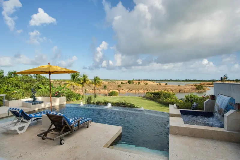 Infinity pool with striped loungers and water view over palm trees