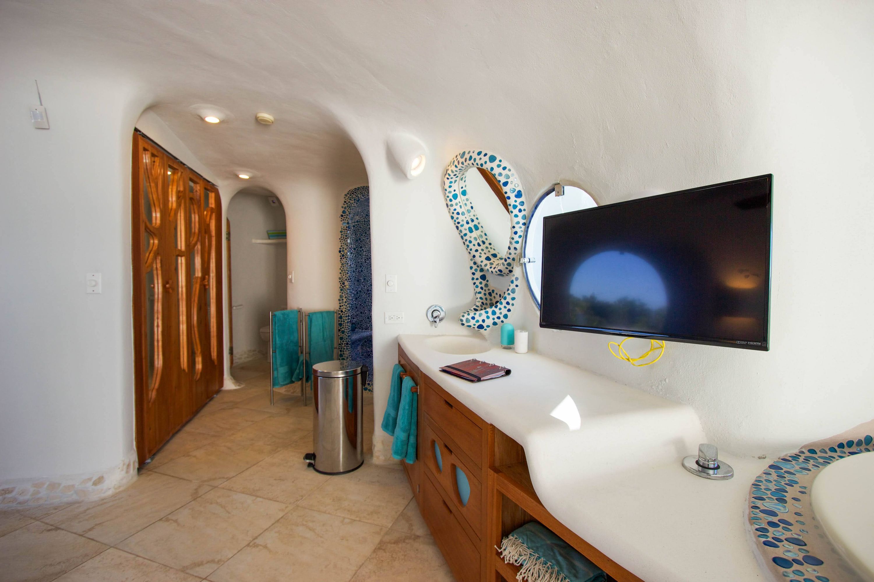 Bathroom vanity with curved wooden cabinet, mosaic mirror and teal towels