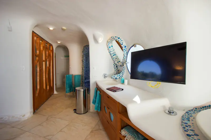 Bathroom vanity with curved wooden cabinet, mosaic mirror and teal towels