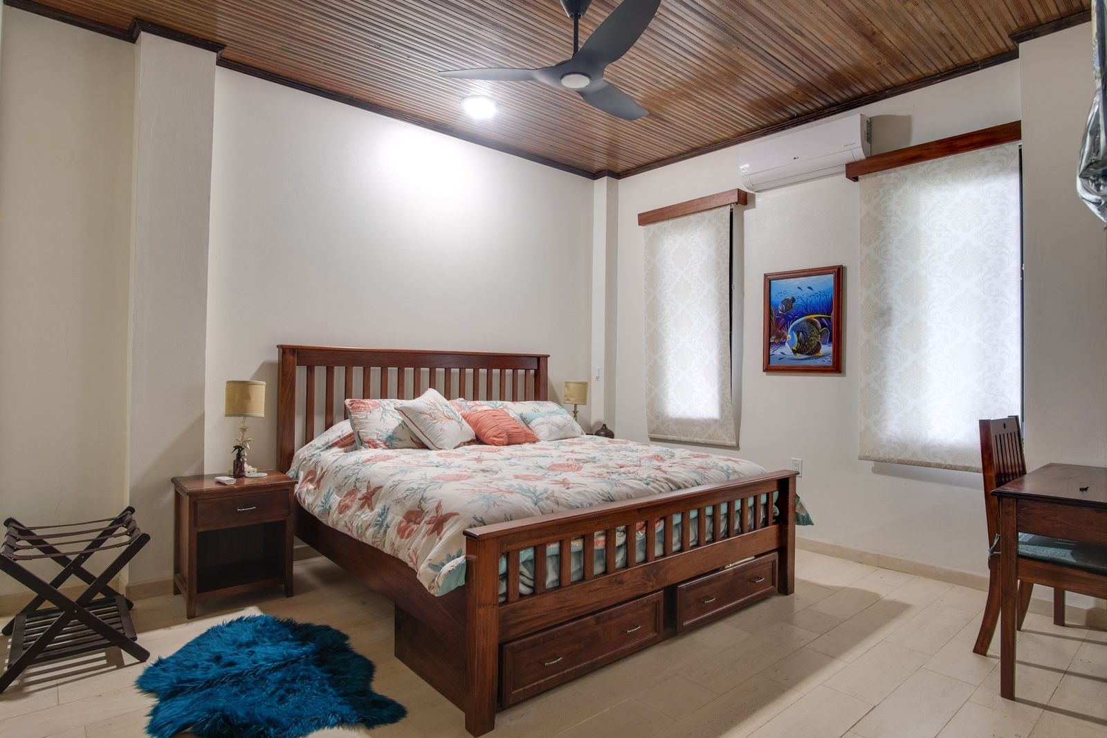 Bedroom with wood-slat bed, coral floral bedding and wood-paneled ceiling