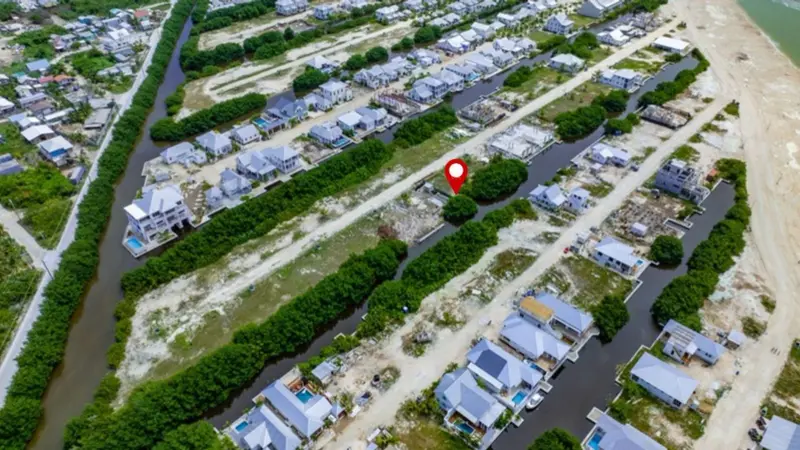 Aerial view of a vacant canal-side lot marked with a red pin, bordered by mangroves