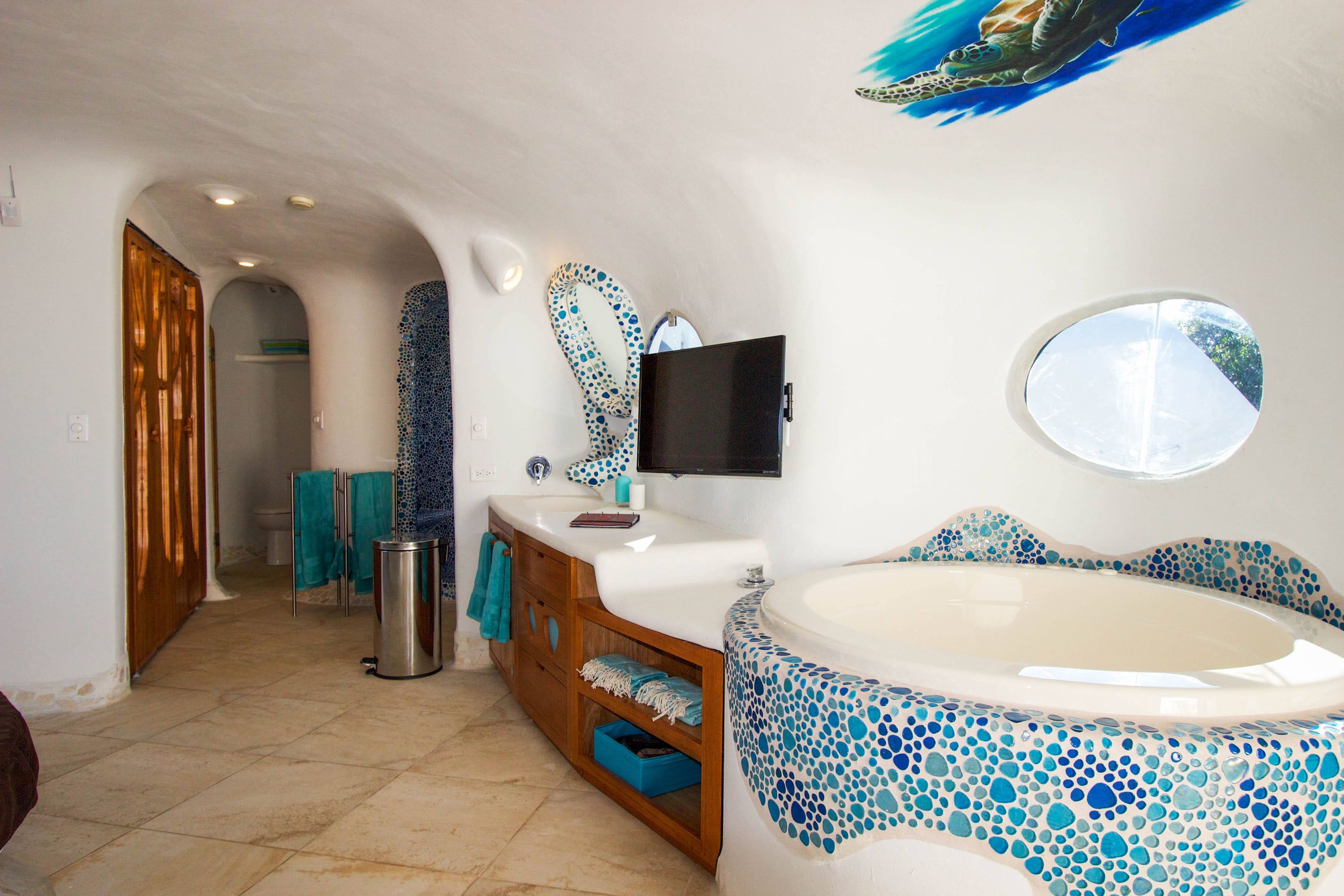 Bathroom vanity with mosaic mirror, wall-mounted TV and blue folded towels