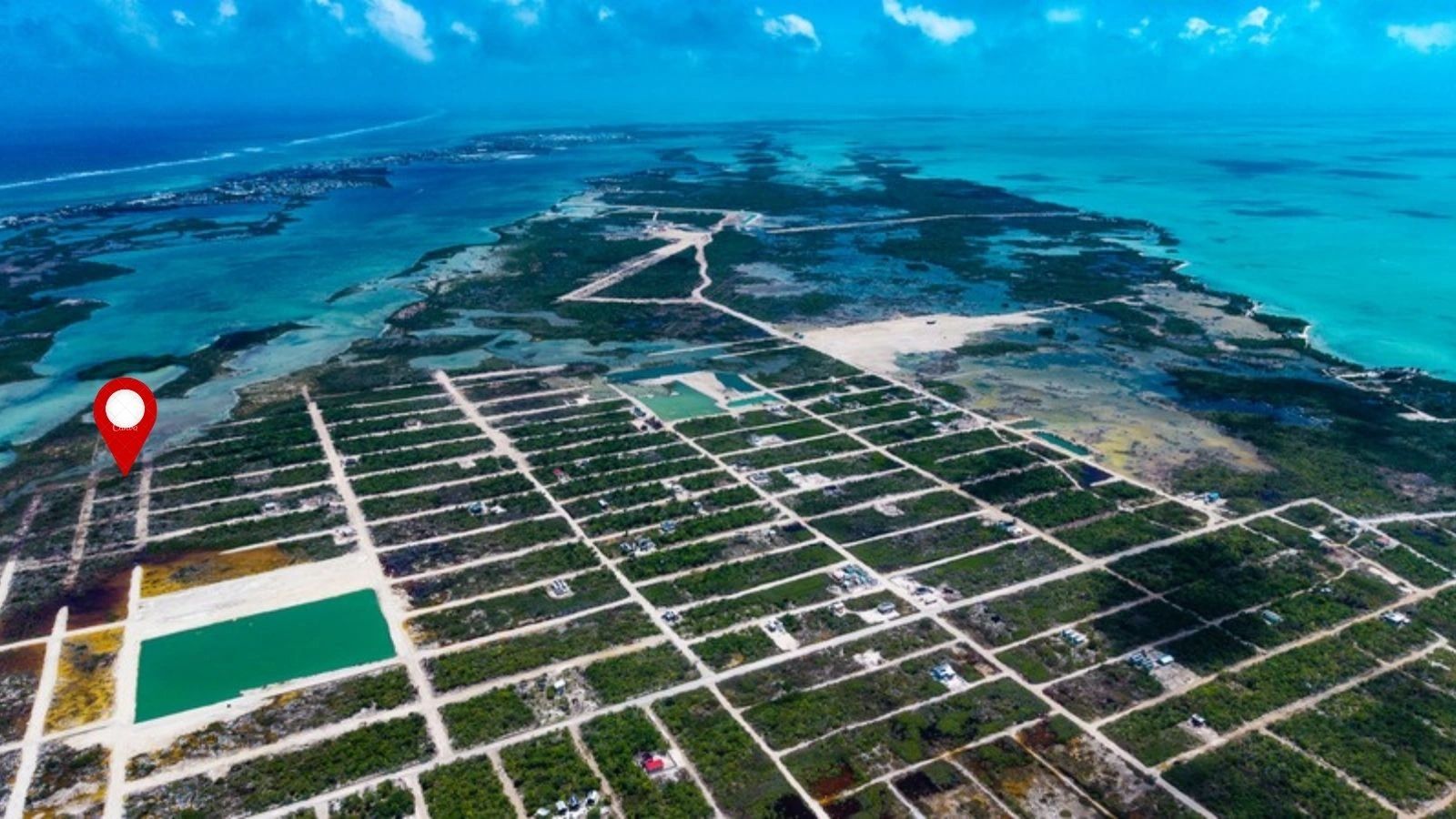 Aerial view of gridded land lots with sandy roads beside turquoise sea