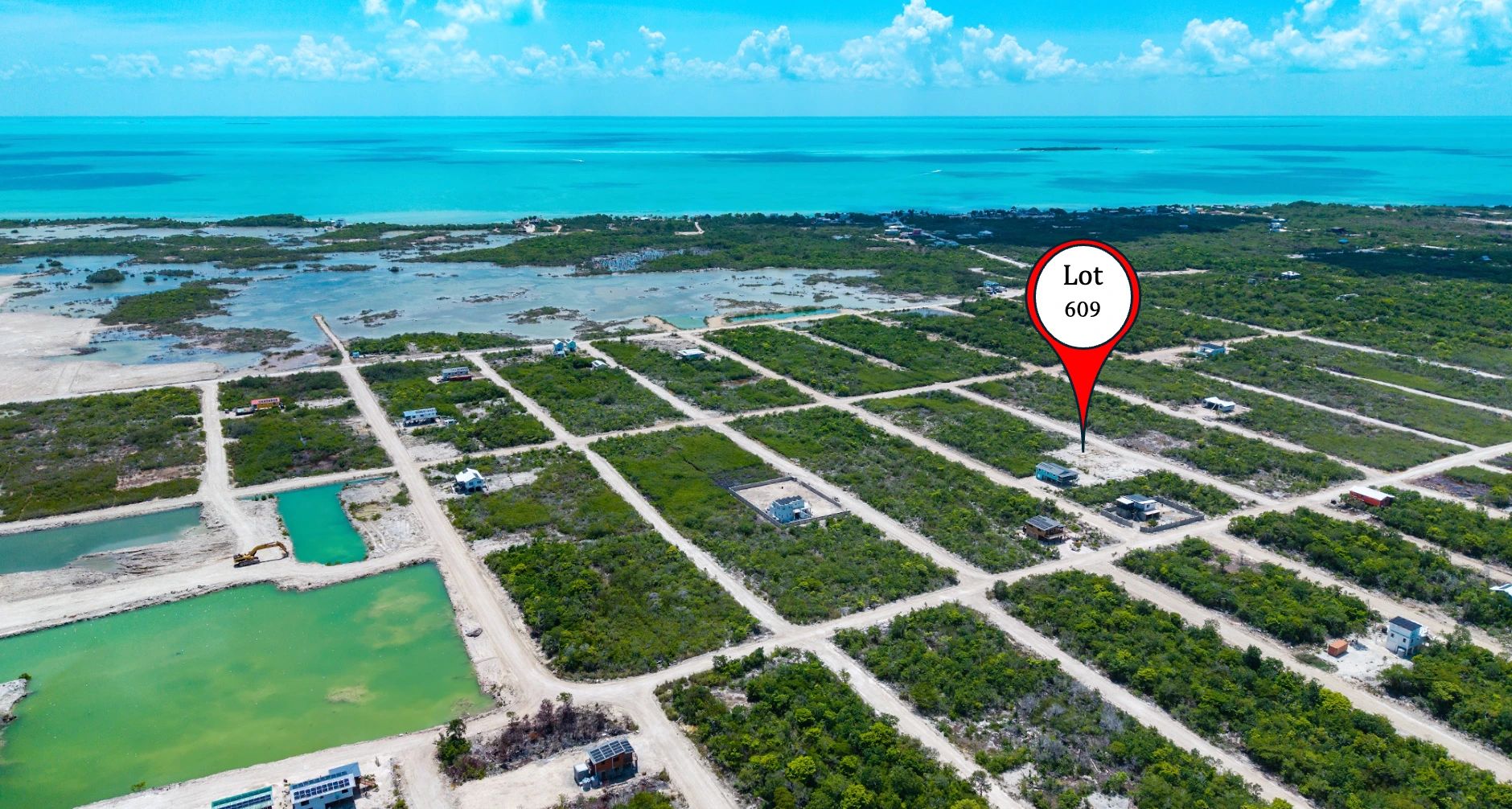 Aerial view of vegetated lots along sandy grid roads near turquoise water