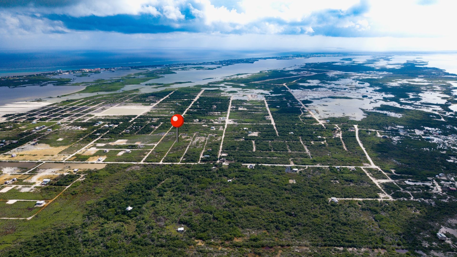 Aerial view of subdivided lots with red location pin near water