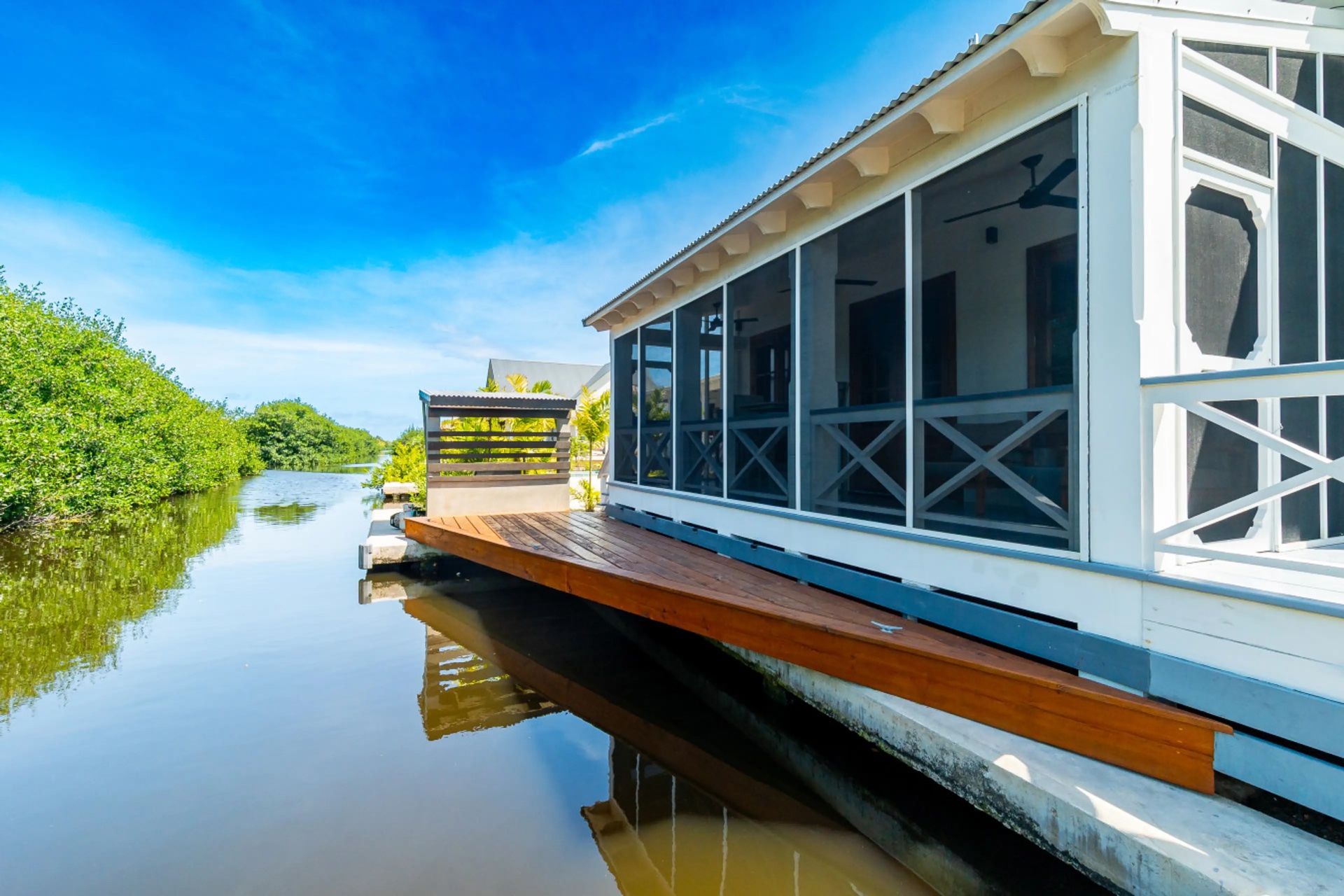 Screened porch with wooden deck extending over the water canal