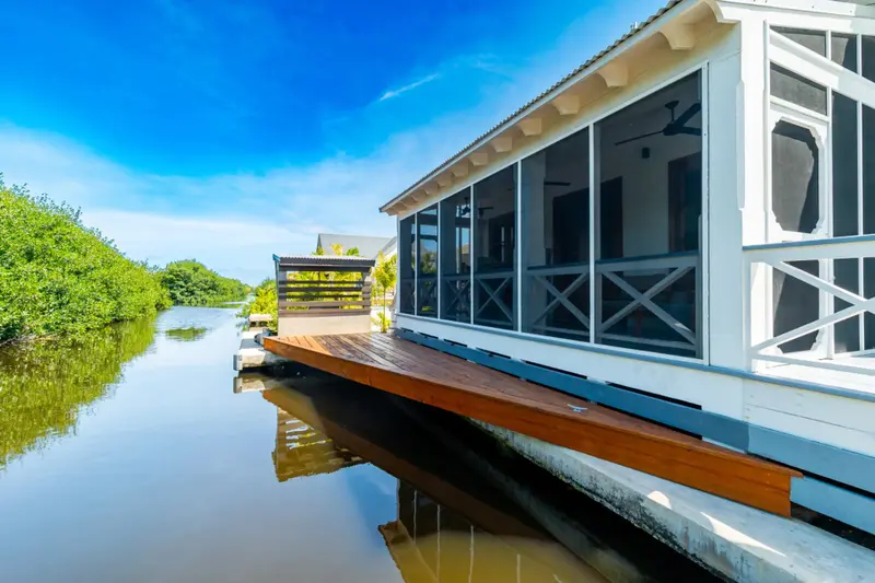 Screened porch with wooden deck extending over the water canal