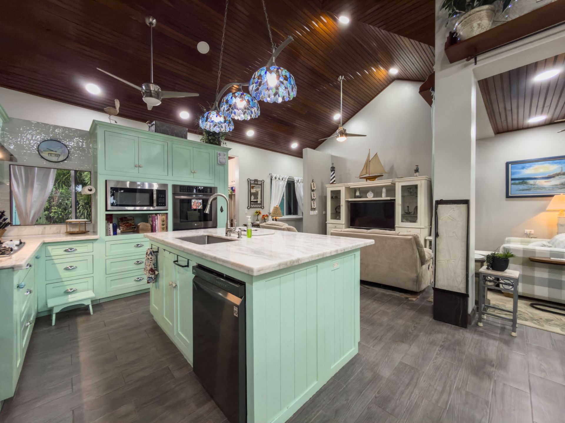 Kitchen island with mint green cabinets, marble top and stained glass pendant lights