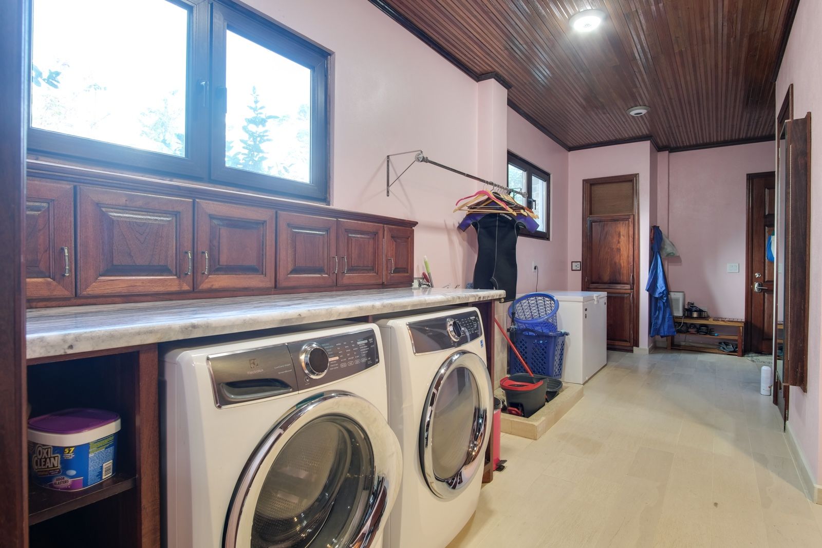 Laundry room with front-loading washer and dryer under wooden cabinets