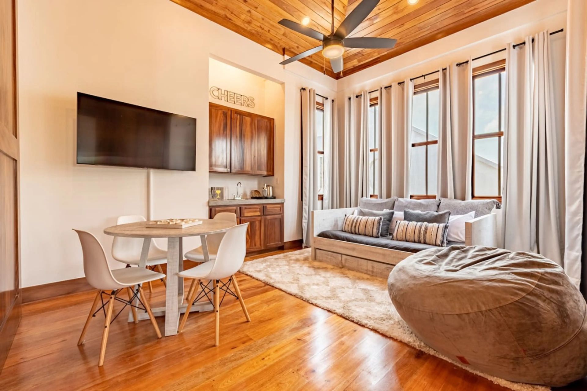 Living room with wood ceiling, ceiling fan, and gray daybed with striped pillows