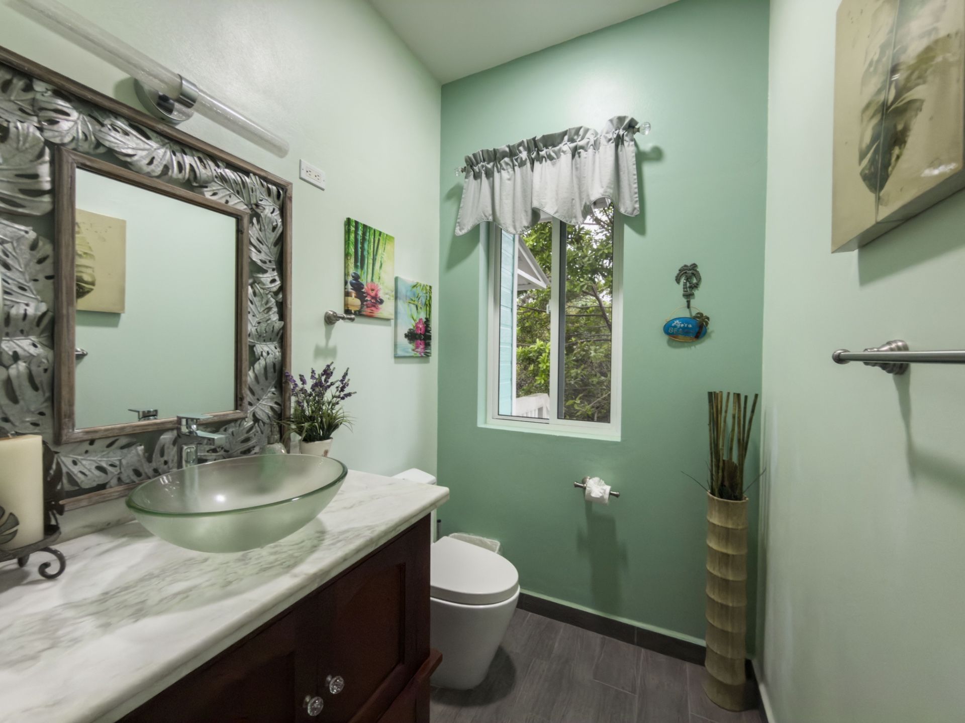 Bathroom with mint green walls, vessel sink and white toilet beside window