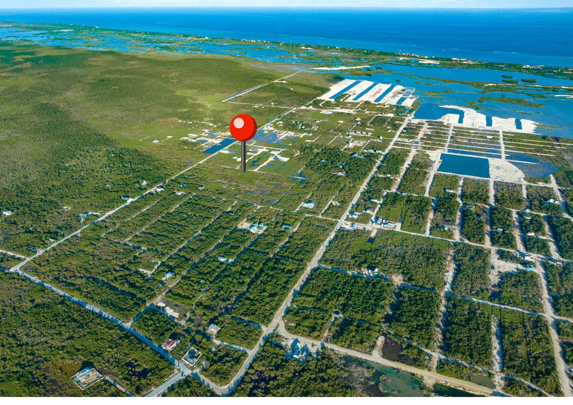 Aerial view of scattered lots with a red map pin and sea beyond