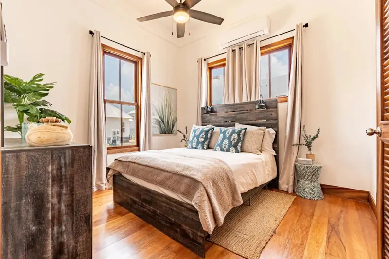 Bedroom with wood platform bed, teal patterned pillows and ceiling fan
