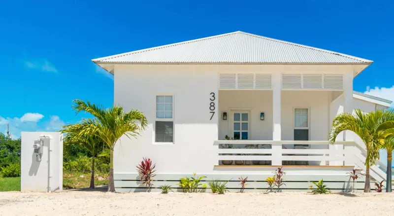 White single-storey house with metal roof, front porch and house number 387